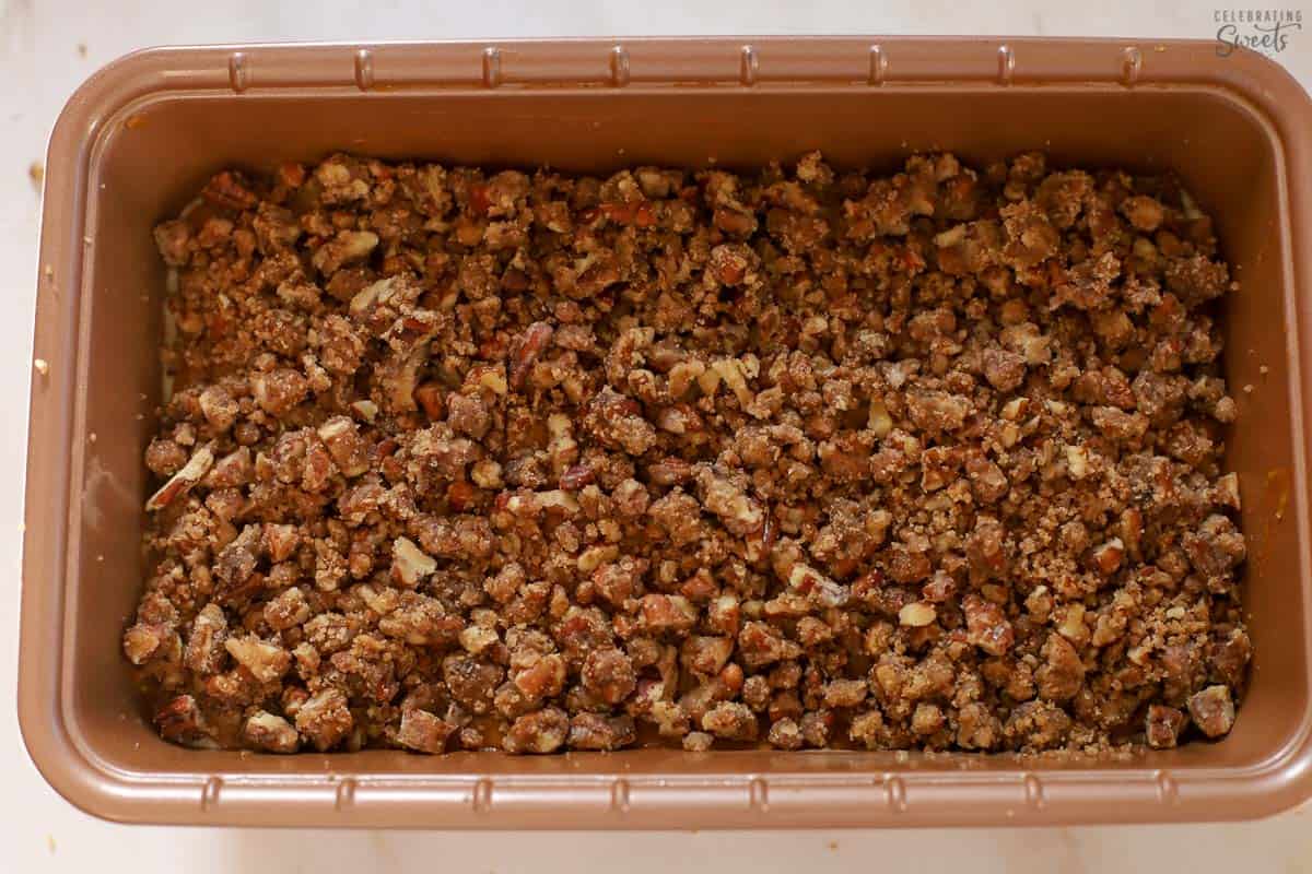 Pumpkin bread topped with pecans in a loaf pan.